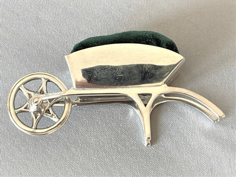 An Edwardian sterling silver pin cushion in the shape of a miniature wheelbarrow with a dark green velvet insert. View VI