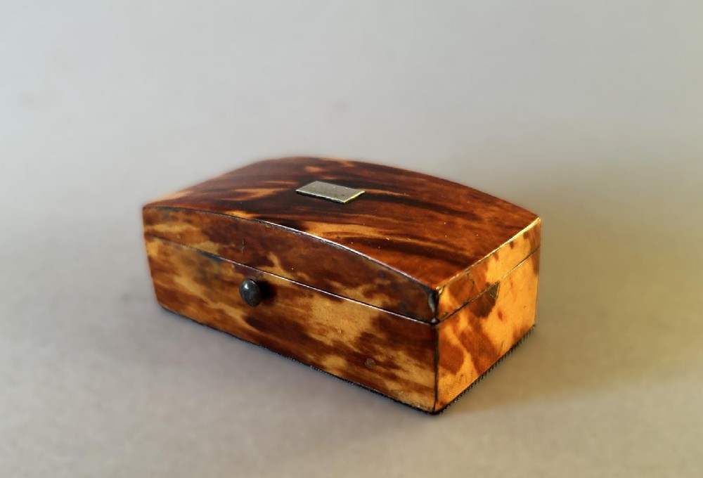 A mid-19th-century rectangular tortoiseshell snuff box featuring a curved top lid and a blank silver cartouche inlay.