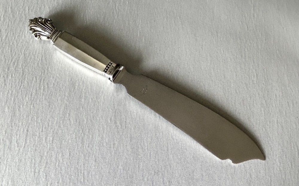 A mid-century Georg Jensen silver serving slice featuring a faceted handle and sculpted leaf finial.