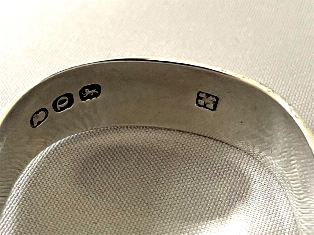 A pair of Georgian sterling silver sugar tongs featuring reeded arms and spoon grips on a grey textured background. View VI