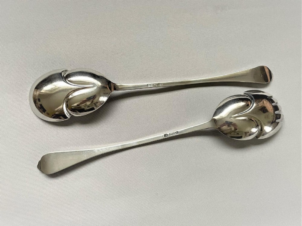 A pair of Edwardian silver salad servers consisting of a spoon and a fork with stylized leaf-shaped bowls and scroll-embossed handle terminals. View II