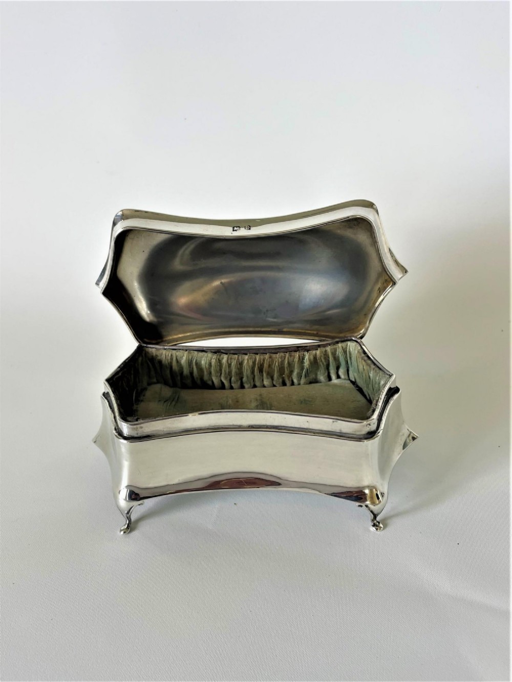 A polished George V sterling silver trinket box featuring a shaped flared body, hinged lid, and four cabriole legs. View III