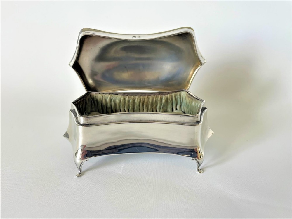 A polished George V sterling silver trinket box featuring a shaped flared body, hinged lid, and four cabriole legs. View IV