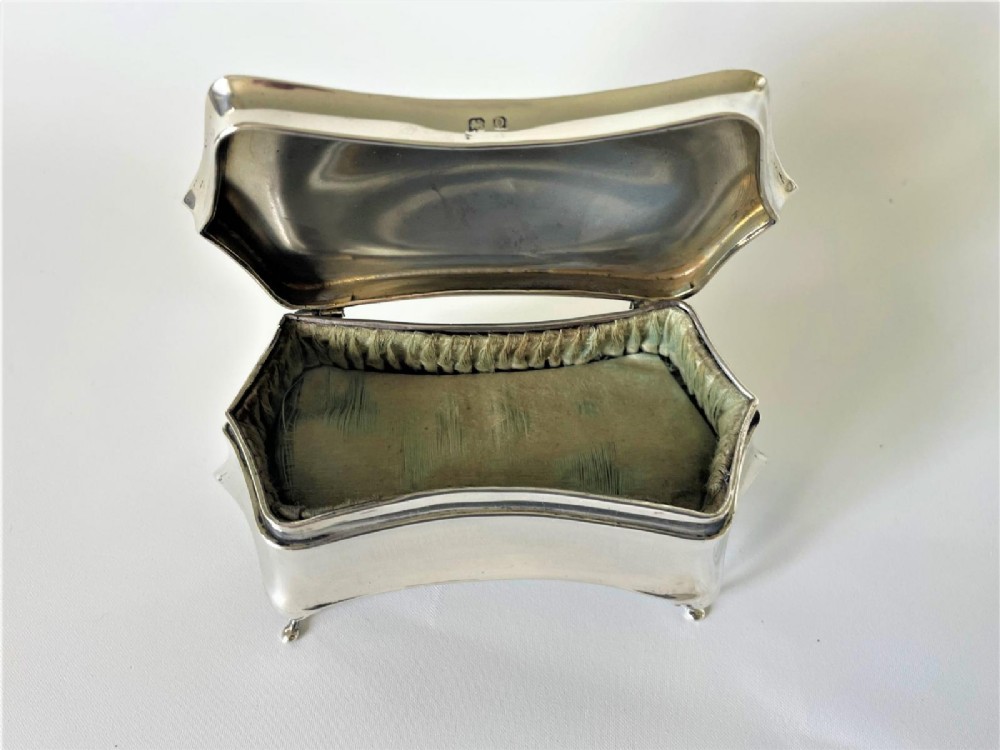 A polished George V sterling silver trinket box featuring a shaped flared body, hinged lid, and four cabriole legs. View VII