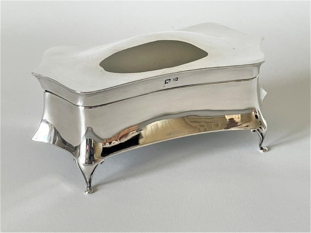 A polished George V sterling silver trinket box featuring a shaped flared body, hinged lid, and four cabriole legs. View VIII