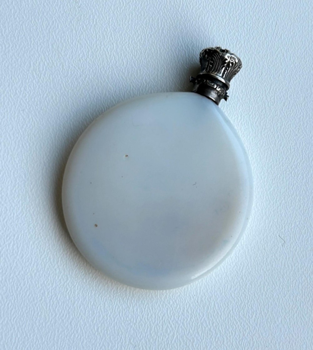 A circular white opaline glass scent bottle with a embossed silver cap top. View II