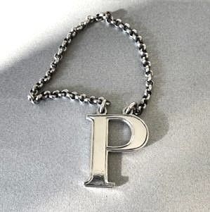 An early Victorian silver decanter label formed in the shape of the letter P and suspended on a silver chain.