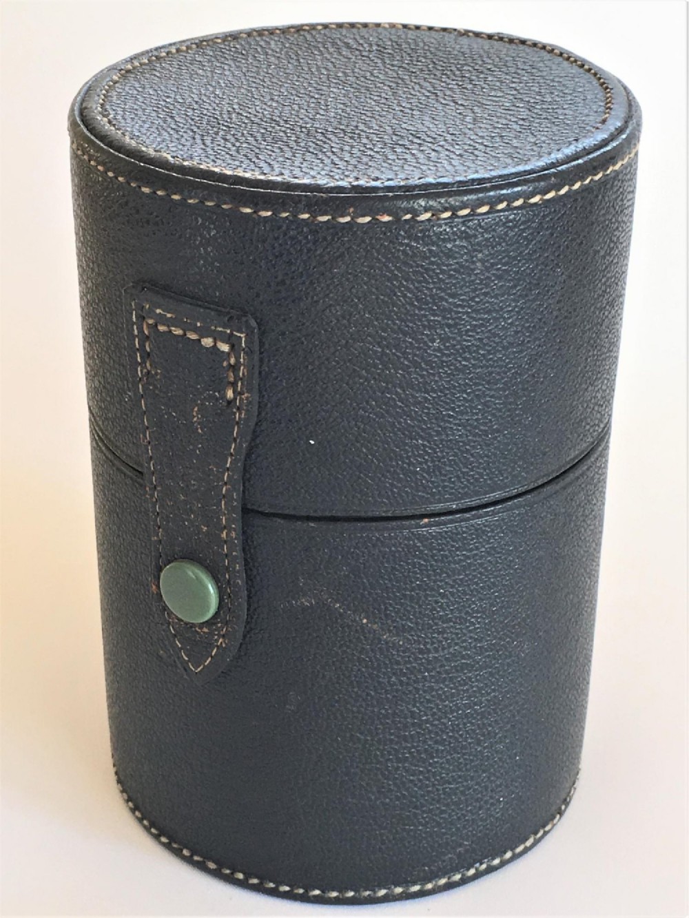 Three wedge-shaped clear glass cologne bottles with silver caps resting beside an open cylindrical black leather travel case. View II