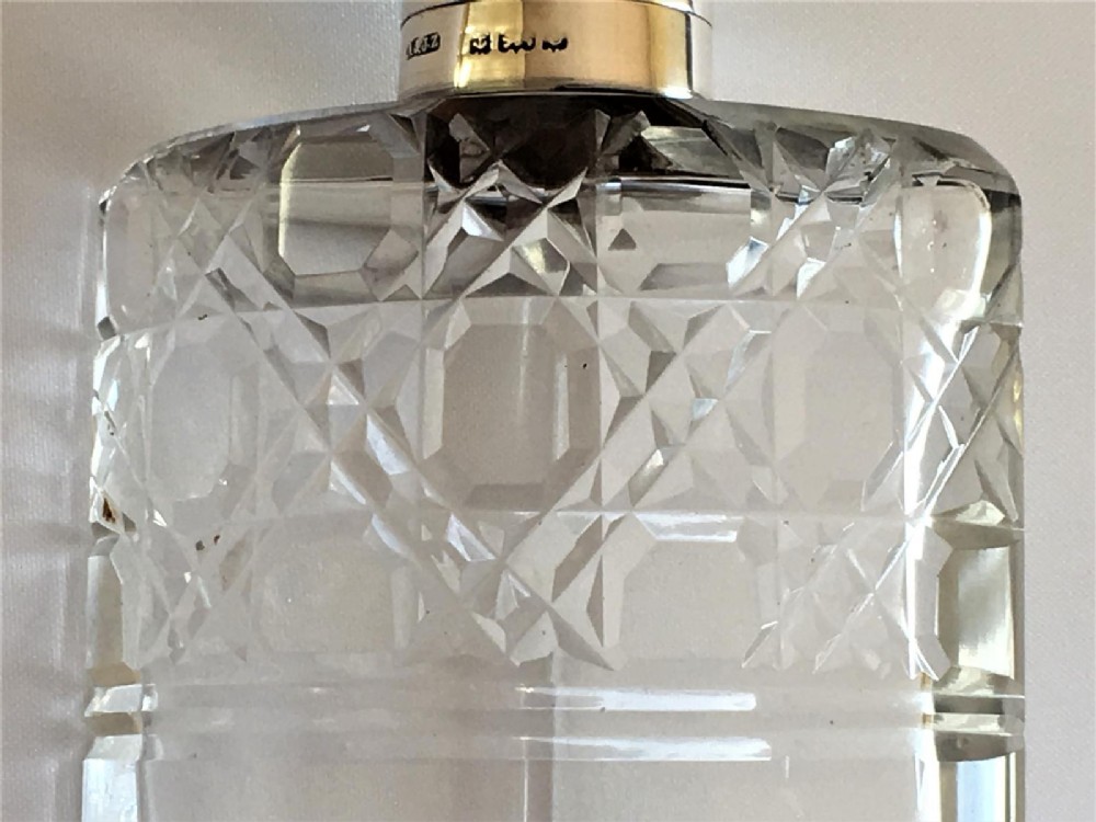 Three wedge-shaped clear glass cologne bottles with silver caps resting beside an open cylindrical black leather travel case. View VI