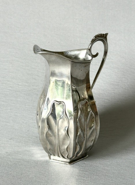 A late Victorian silver cream jug featuring embossed relief leaf motifs around its lower body and a beaded scroll handle. View II