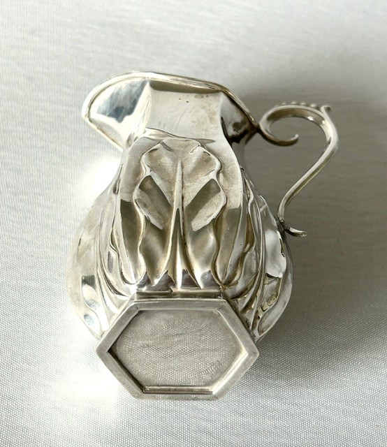 A late Victorian silver cream jug featuring embossed relief leaf motifs around its lower body and a beaded scroll handle. View IV