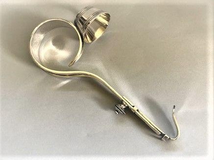 An Edwardian silver-plated champagne bottle holder featuring an adjustable collar mechanism and a curved pouring handle.