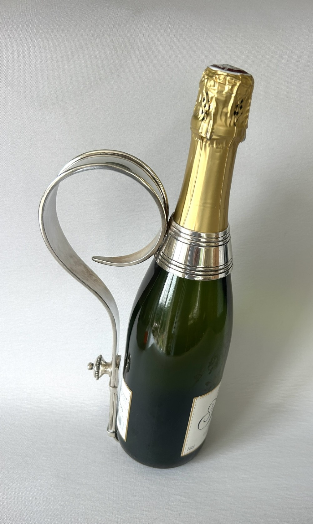 An Edwardian silver-plated champagne bottle holder featuring an adjustable collar mechanism and a curved pouring handle. View VII