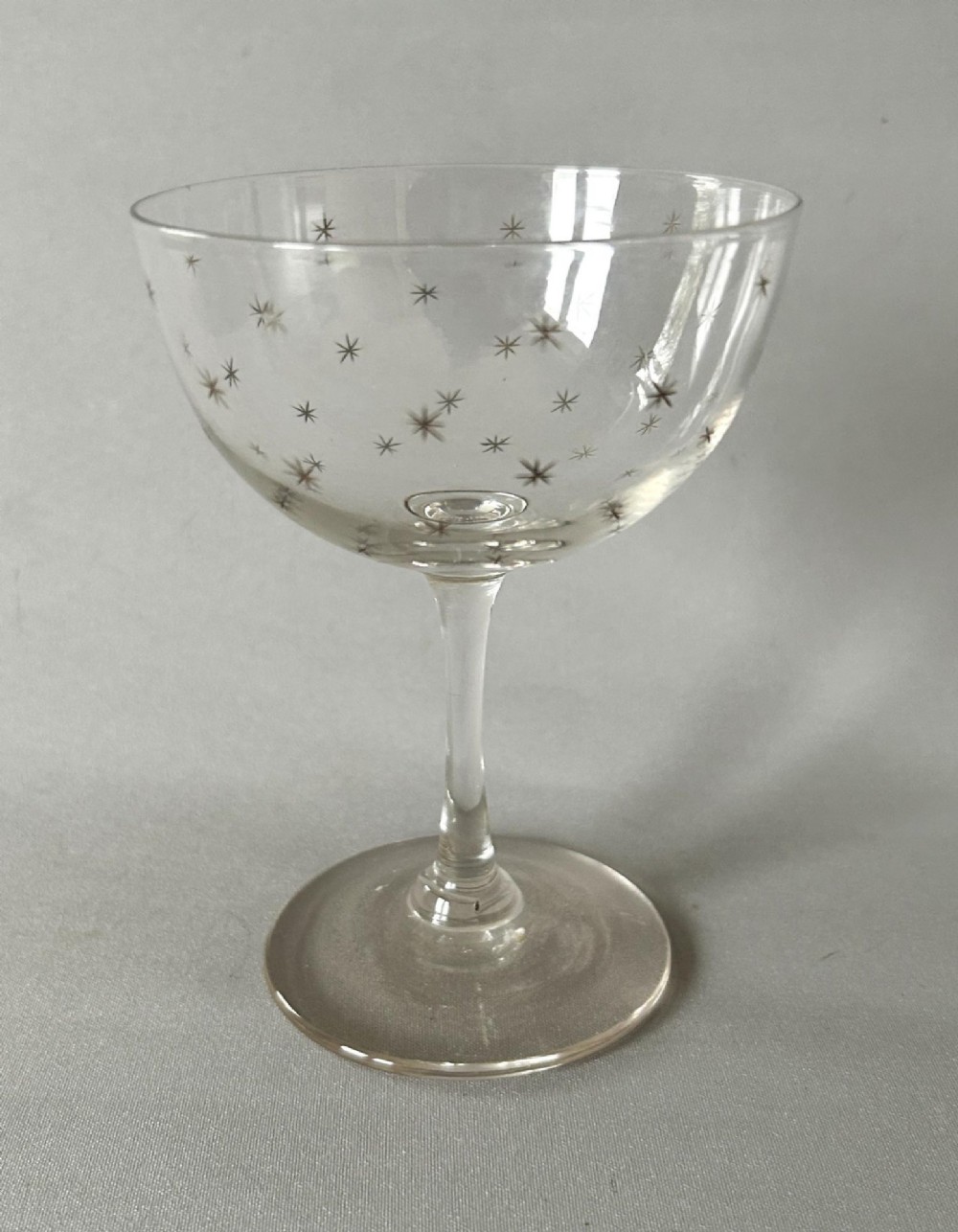 A harlequin set of six clear Victorian glass champagne coupes featuring varied etched motifs including starbursts and Greek key patterns. View II
