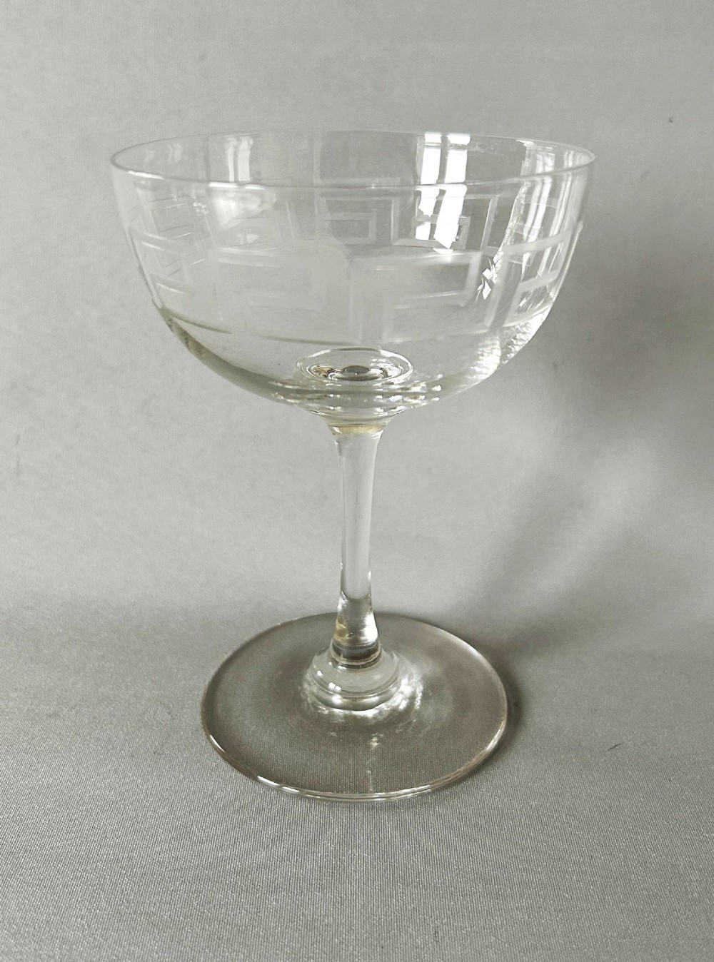 A harlequin set of six clear Victorian glass champagne coupes featuring varied etched motifs including starbursts and Greek key patterns. View VI