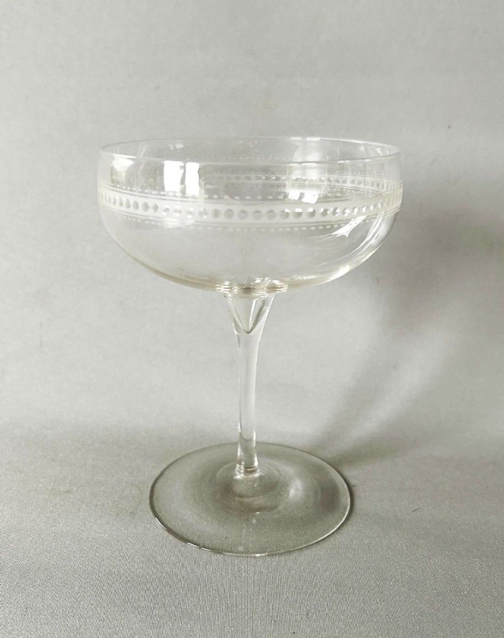 A harlequin set of six clear Victorian glass champagne coupes featuring varied etched motifs including starbursts and Greek key patterns. View VIII