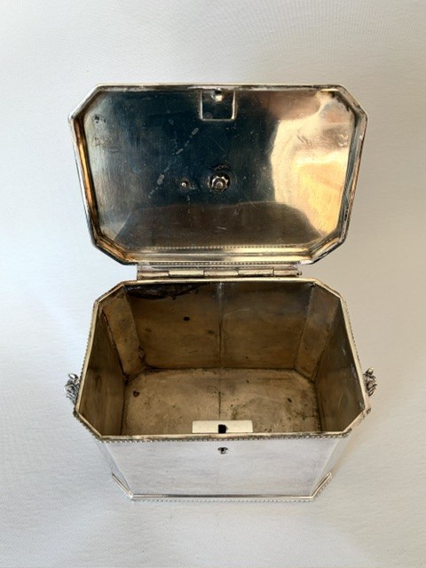 A silver-plated rectangular box with canted corners, featuring a horse finial on the lid, horse head handles on the sides, and a central keyhole. View V