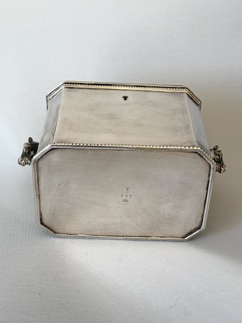 A silver-plated rectangular box with canted corners, featuring a horse finial on the lid, horse head handles on the sides, and a central keyhole. View VIII