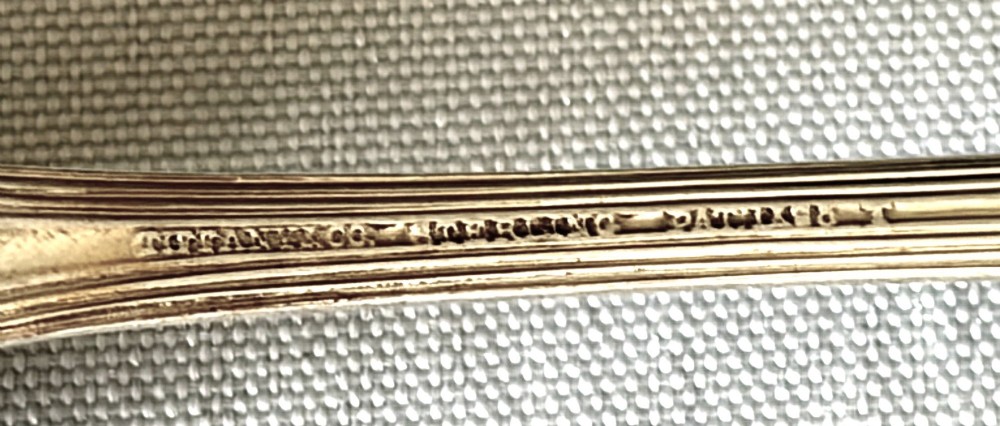 A long-handled Tiffany sterling silver condiment ladle featuring a round bowl and Colonial pattern shell terminal. View III