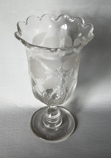 A clear glass Victorian celery vase featuring an etched floral pattern, a scalloped frilled rim, and a stemmed circular foot. View II