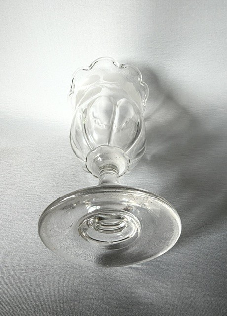 A clear glass Victorian celery vase featuring an etched floral pattern, a scalloped frilled rim, and a stemmed circular foot. View VI