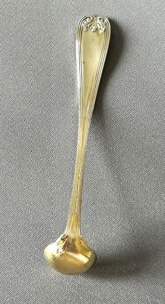 A long-handled Tiffany sterling silver condiment ladle featuring a round bowl and Colonial pattern shell terminal. View V