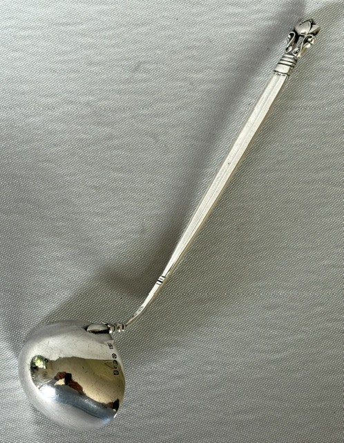 A sterling silver small sauce ladle featuring a rounded bowl attached to a tapered stem with a stylized acorn cap finial. View V