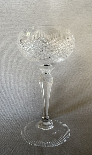 A set of six clear cut glass champagne coupes featuring faceted stems and diamond-cut bowls arranged on a neutral background. View VI