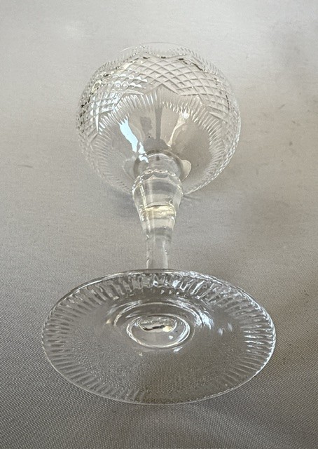 A set of six clear cut glass champagne coupes featuring faceted stems and diamond-cut bowls arranged on a neutral background. View VII