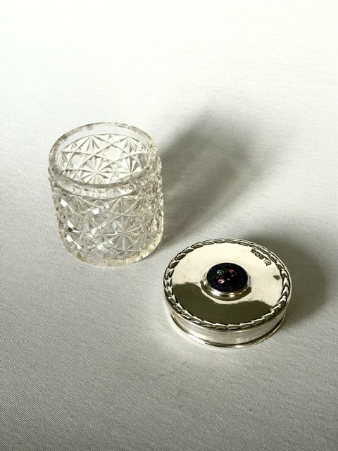 A round cut glass vanity jar topped with a hallmarked sterling silver lid featuring a central blue floral enamel motif. View VIII