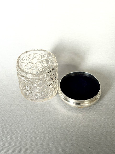 A round cut glass vanity jar topped with a hallmarked sterling silver lid featuring a central blue floral enamel motif. View IX