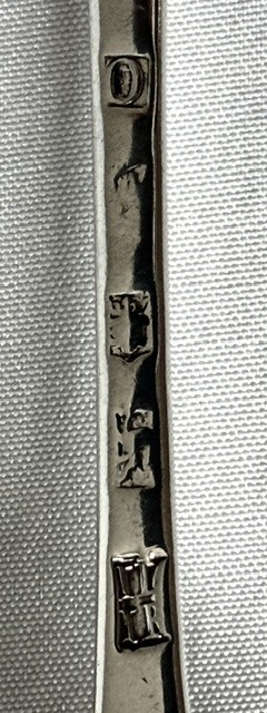 An 18th-century sterling silver serving spoon featuring an oval bowl and a tapered stem stamped with provincial hallmarks near the terminal. View V