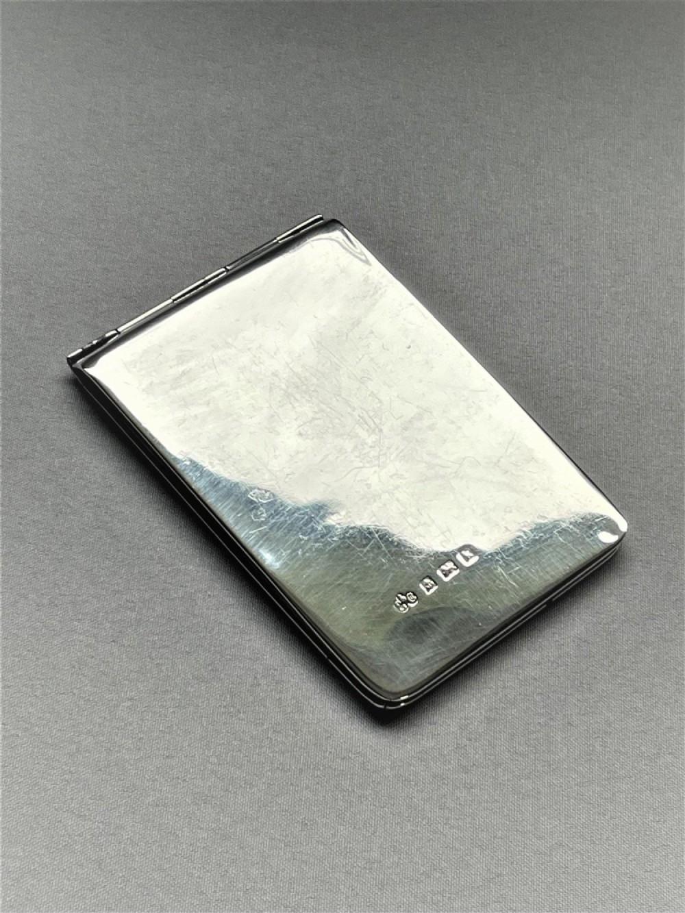 A rectangular Edwardian sterling silver wallet and stamp case displaying visible British silver hallmarks on its smooth metallic exterior.
