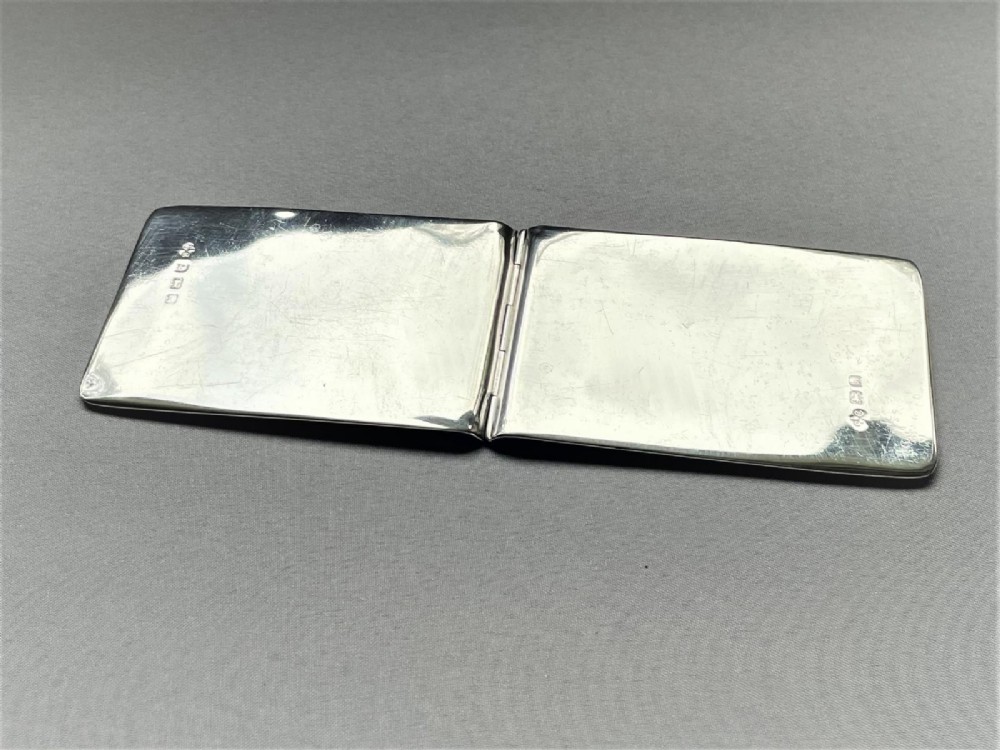 A rectangular Edwardian sterling silver wallet and stamp case displaying visible British silver hallmarks on its smooth metallic exterior. View V