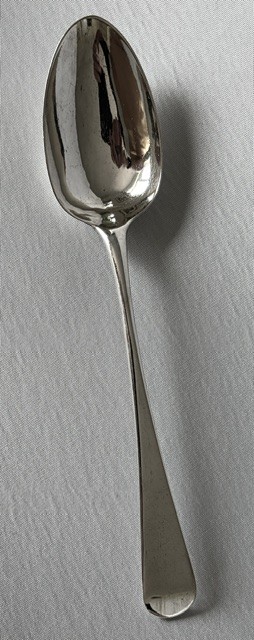 A Georgian sterling silver tablespoon featuring an elongated oval bowl and a smooth tapered stem against a light grey background. View IV