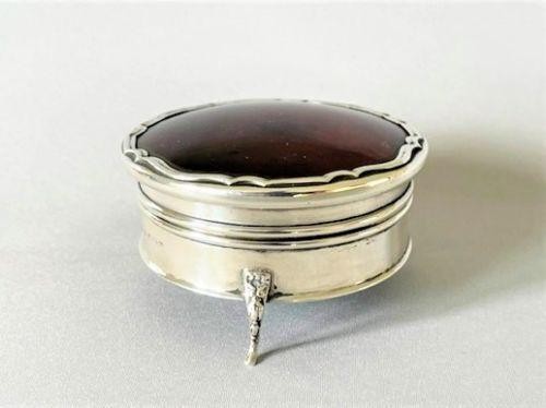 A circular George V sterling silver trinket box featuring a dark tortoiseshell lid with a scalloped edge resting on three silver legs. View III