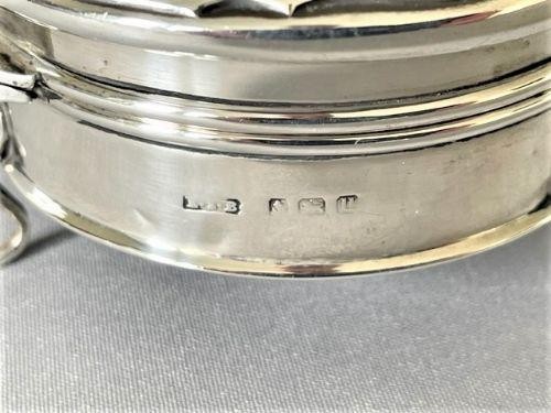 A circular George V sterling silver trinket box featuring a dark tortoiseshell lid with a scalloped edge resting on three silver legs. View IV