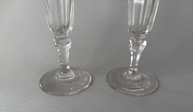 A pair of clear early Victorian cut glass champagne flutes featuring flared rims, faceted stems, and slice-cut lower bowls on flat circular bases. View II