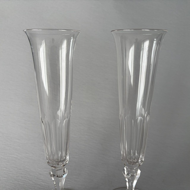 A pair of clear early Victorian cut glass champagne flutes featuring flared rims, faceted stems, and slice-cut lower bowls on flat circular bases. View III