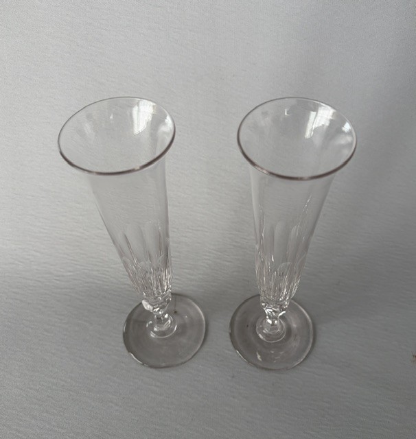 A pair of clear early Victorian cut glass champagne flutes featuring flared rims, faceted stems, and slice-cut lower bowls on flat circular bases. View IV
