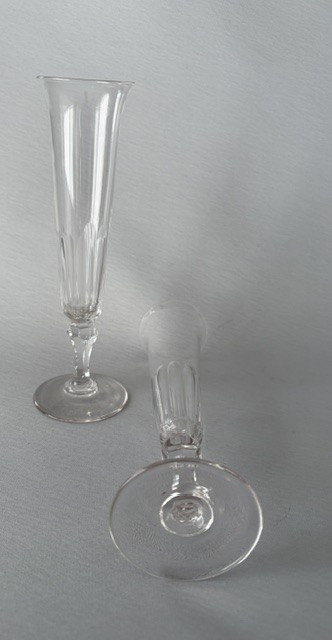 A pair of clear early Victorian cut glass champagne flutes featuring flared rims, faceted stems, and slice-cut lower bowls on flat circular bases. View VI