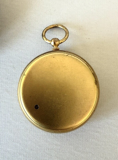 An Edwardian brass pocket barometer and altimeter displayed inside an open plush-lined maroon leather case. View V