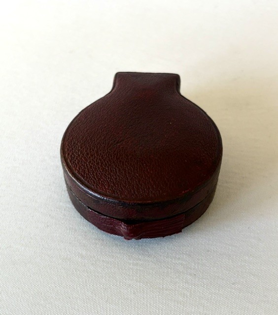 An Edwardian brass pocket barometer and altimeter displayed inside an open plush-lined maroon leather case. View VI