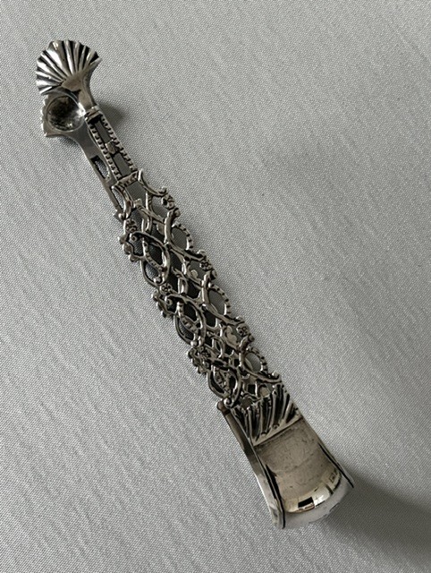 A pair of 18th-century cast silver sugar tongs featuring openwork lattice arms and shell-shaped grips. View VII