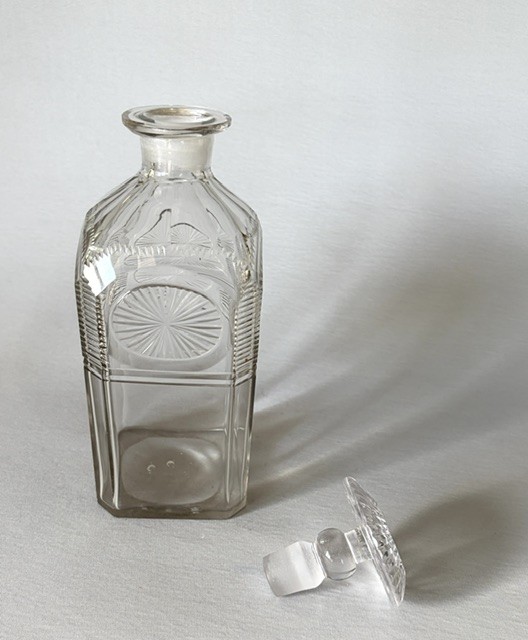 A square clear cut glass decanter featuring wheel-cut starburst motifs, faceted shoulders, and a flat mushroom stopper. View IV