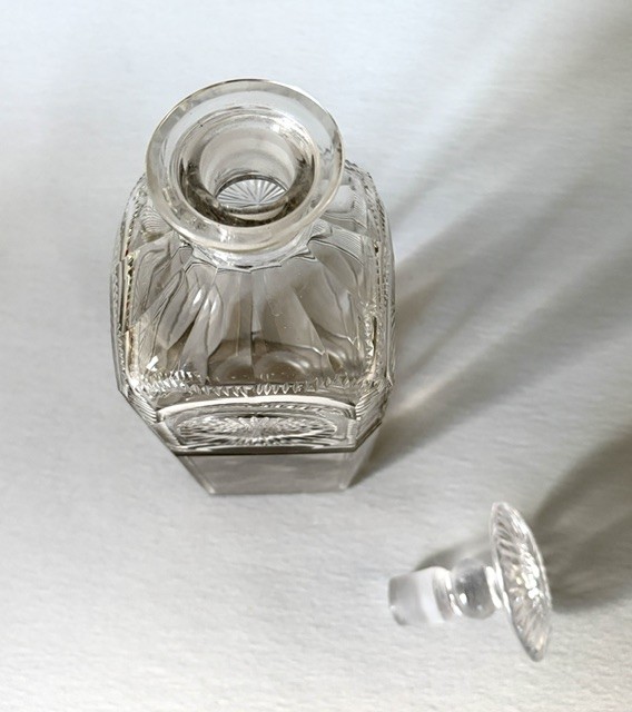 A square clear cut glass decanter featuring wheel-cut starburst motifs, faceted shoulders, and a flat mushroom stopper. View V