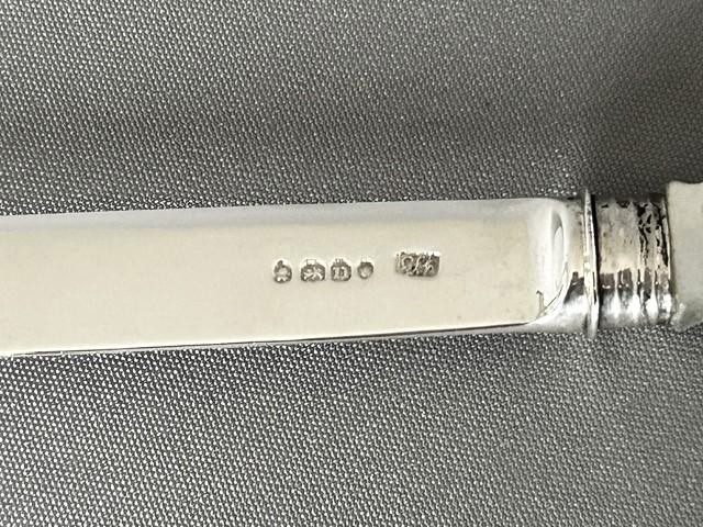 An antique Georgian letter opener featuring a tapered silver blade with stamped hallmarks and a carved cream mother of pearl handle. View II
