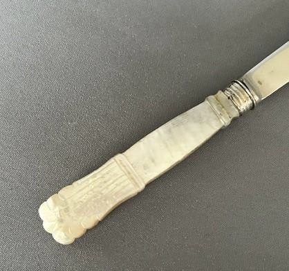 An antique Georgian letter opener featuring a tapered silver blade with stamped hallmarks and a carved cream mother of pearl handle. View IV