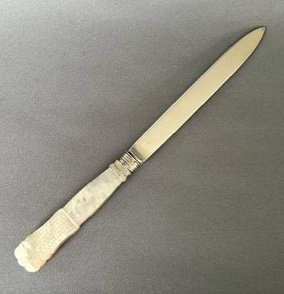 An antique Georgian letter opener featuring a tapered silver blade with stamped hallmarks and a carved cream mother of pearl handle. View V