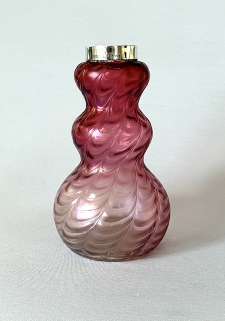 An Art Nouveau iridescent glass vase featuring a lobed, swirling magenta to pink body fitted with a polished sterling silver rim collar. View III
